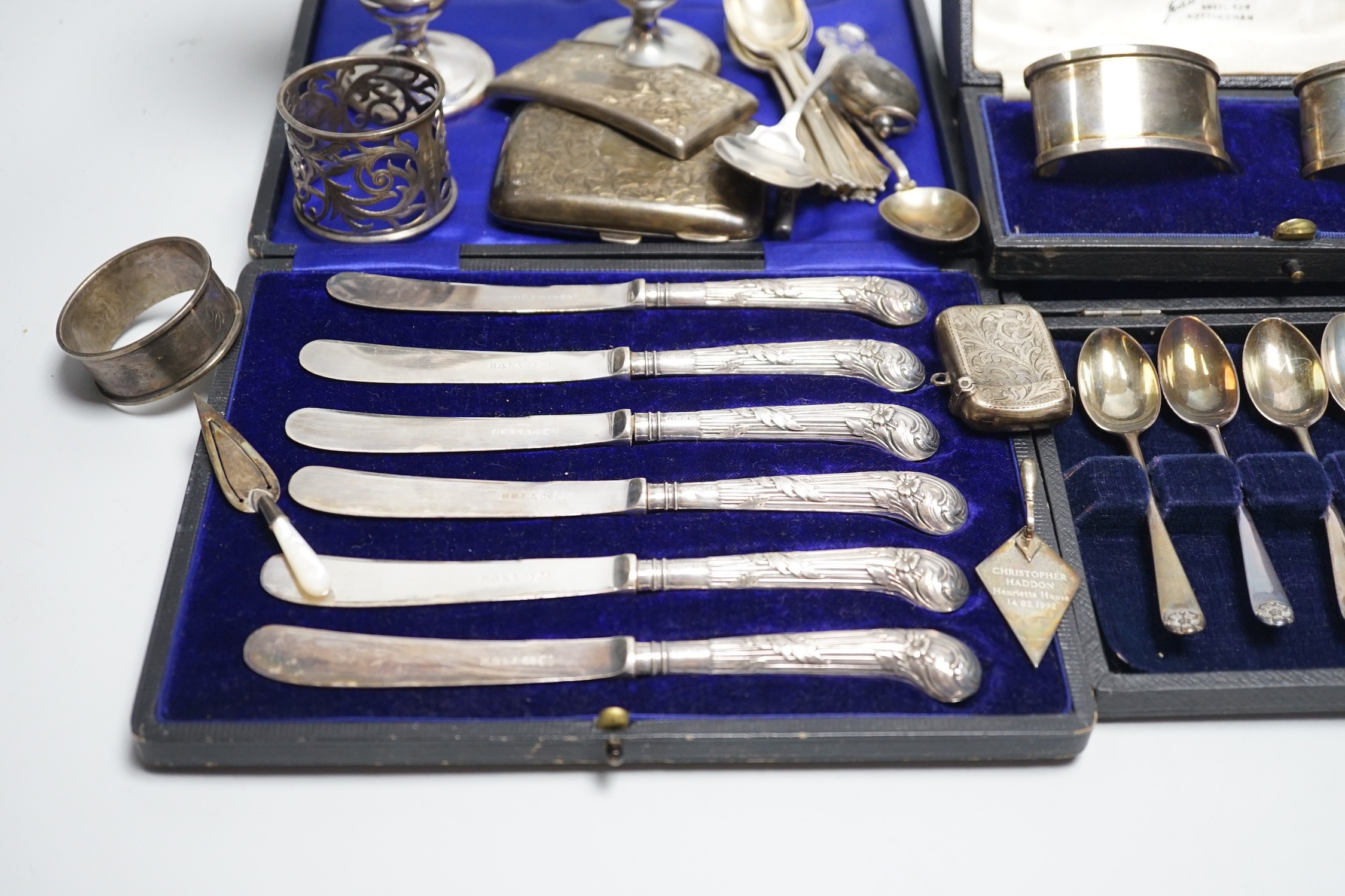 A mixed group of assorted silver ware including a pair of vases, 13.1cm, weighted, cased and loose napkin rings, cased teaspoons, cased silver pistol handled tea knives, sovereign case, mother of pearl handled fruit knif